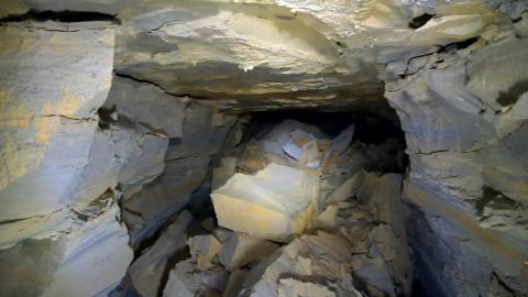 Layers of rock surround a dark mine opening. 