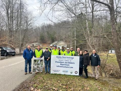 A group of Interior and OSMRE officials stand with an Infrastructure Act sign